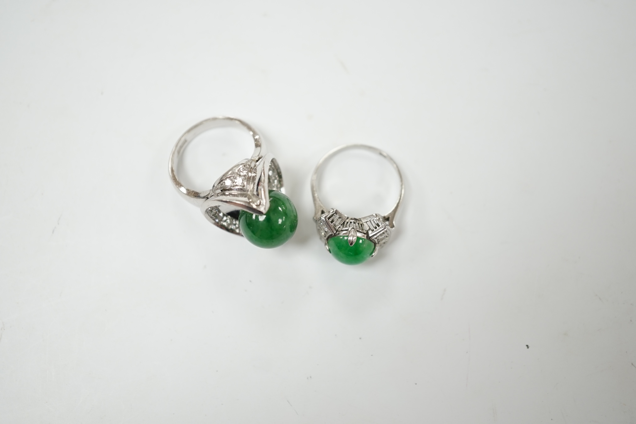 A modern white metal (stamped Pt) and jade bead set ring, with diamond set shoulders, size J/K, together with a similar larger white metal jade bead and diamond set ring, size I/J, gross weight 19.9 grams. Condition - fa
